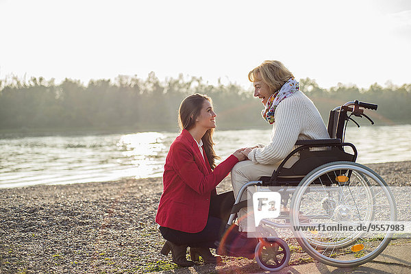 Enkelin,  die ihrer Großmutter im Rollstuhl assistiert