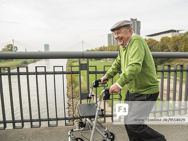 Playful senior man with wheeled walker on bridge