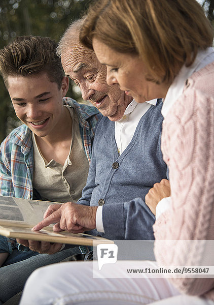 Senior Mann mit Enkel und Tochter beim Betrachten des Fotoalbums