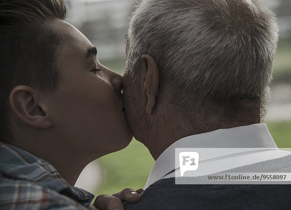 Enkel  der die Wange eines älteren Mannes küsst.