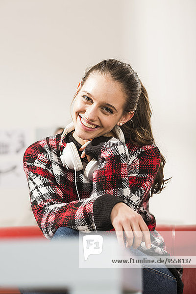 Portrait of smiling young woman with headphones at home