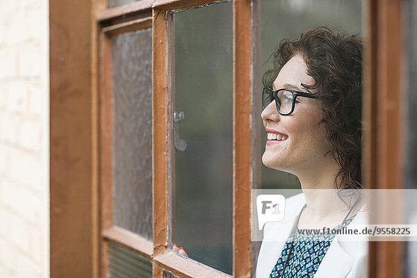 Smiling young businesswoman looking out of window