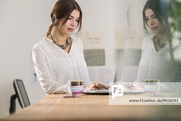 Young businesswoman using laptop in office