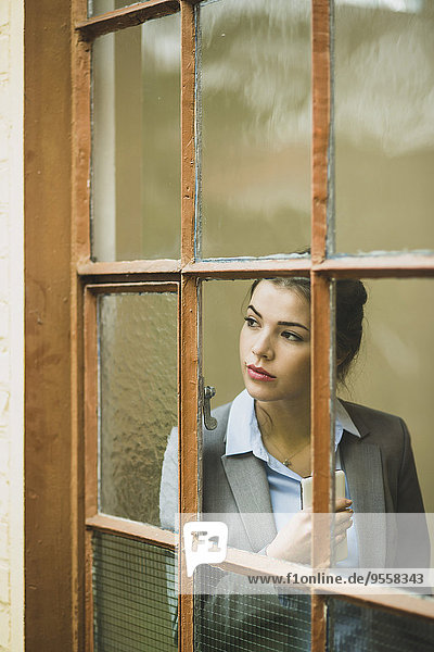 Serious young businesswoman looking out of window