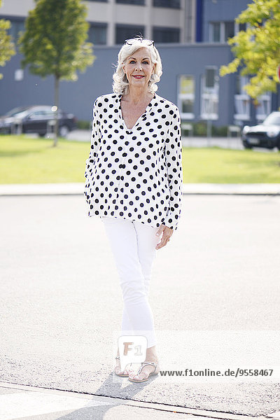 Porträt der weißhaarigen Seniorin in weißer Bluse mit schwarzen Punkten