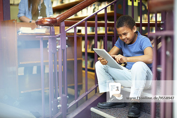 Junge mit digitalem Tablett in der Bibliothek