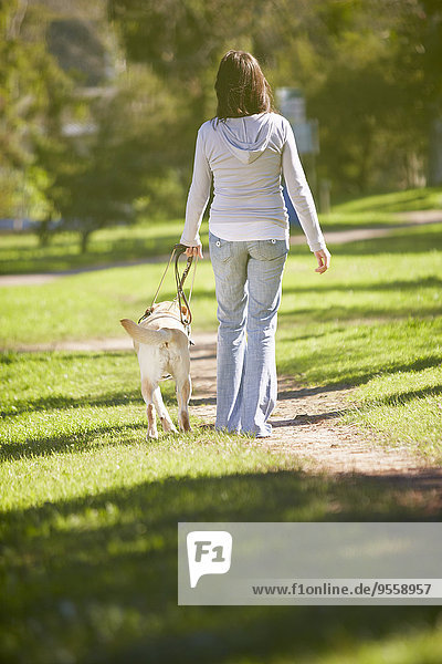 Sehbehinderte Frau beim Spaziergang mit Blindenhund im Park