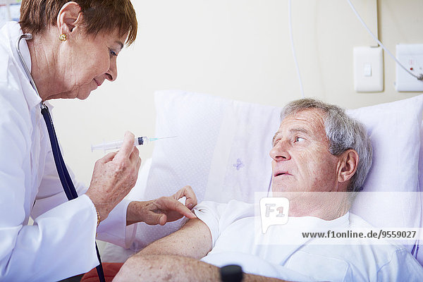 Arzt injiziert älteren Mann im Krankenhausbett