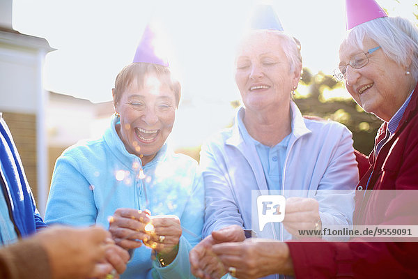 Seniorenfreunde  die auf einer Geburtstagsparty eine Wunderkerze anzünden
