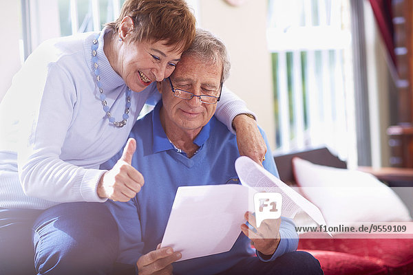 Glückliches Seniorenpaar liest Dokument zu Hause