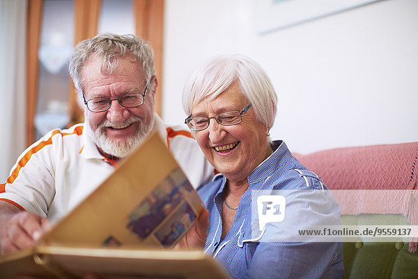 Senior couple at home looking at photo album