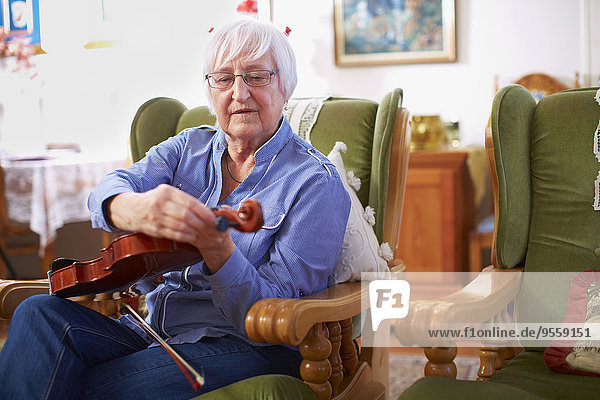 Seniorin zu Hause beim Stimmen der Geige