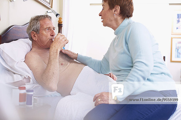 Seniorin  die sich zu Hause um ihren kranken Mann kümmert.