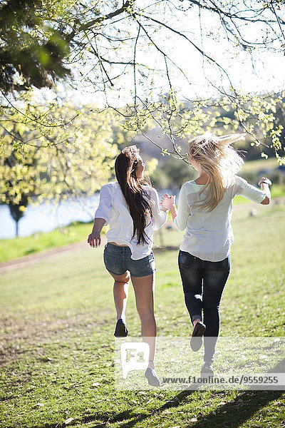 Zwei Freundinnen  die zusammen in einem Park laufen