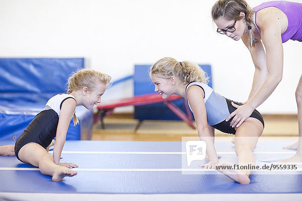 Trainerin mit zwei Mädchen beim Gymnastizieren am Boden
