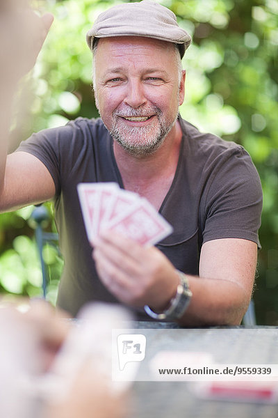 Lächelnder reifer Mann beim Kartenspielen