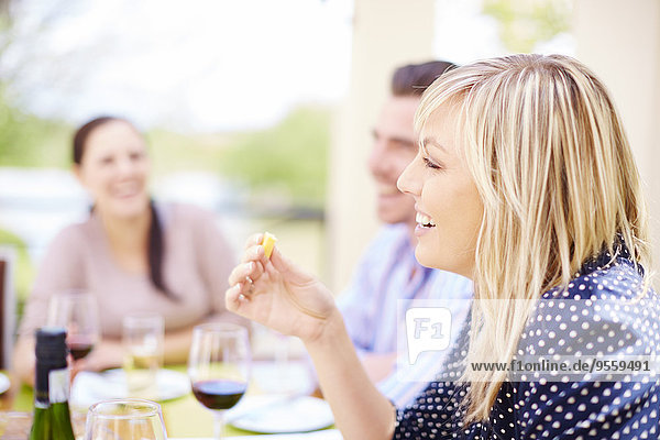 Lächelnde Frau beim Abendessen mit Freunden