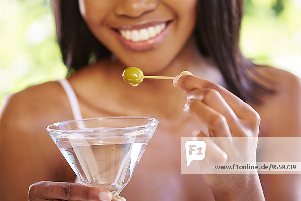 Woman's hands holding cocktail glass with Martini and skewered green olive