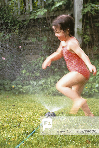Blurred View of Girl in Swimwear Running Through Sprinkler