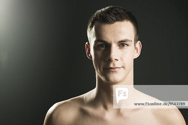 Close-up portrait of young man looking at camera  studio shot on black background