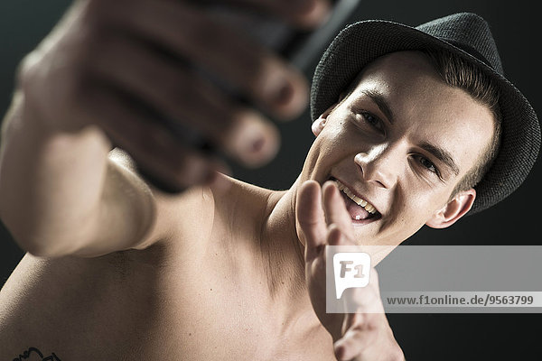 Handy Portrait Mann nehmen Filzhut schwarz Hintergrund Close-up jung Kleidung schießen Studioaufnahme
