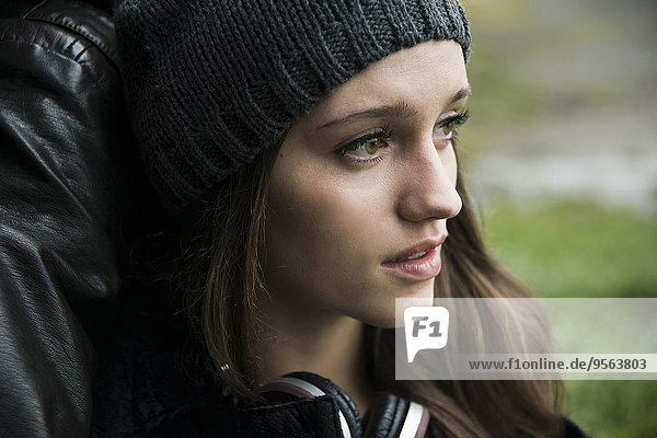 Close-up portrait of teenage girl outdoors  wearing hat and headphones around neck  Germany