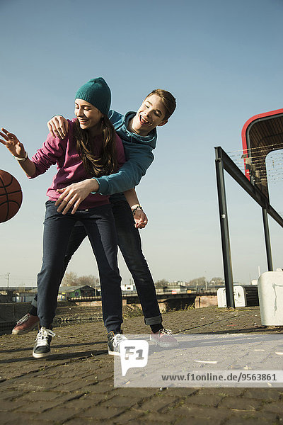 Teenage boy and girl playing basketball outdoors  industrial area  Mannheilm  Germany