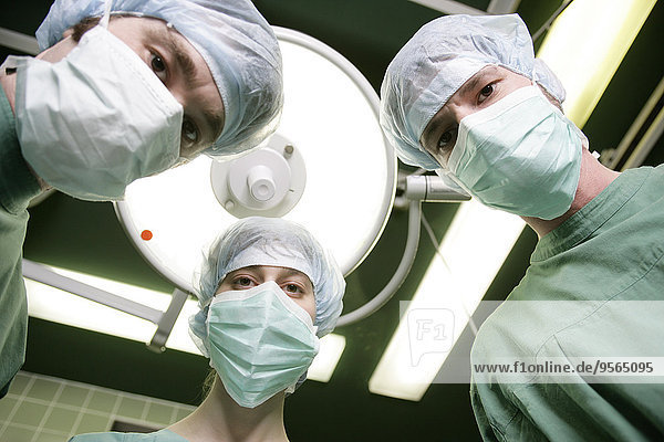 Drei Chirurgen schauen nach unten
