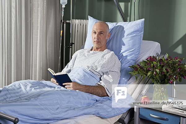 Portrait of a man sitting with a book in a hospital bed