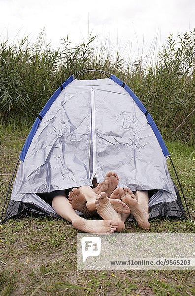 Four barefoot people sharing a tent