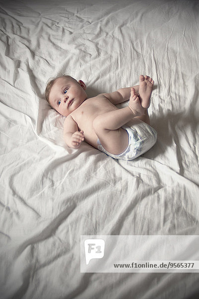 Baby in diaper lying on back with legs up