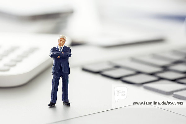 Geschäftsmann-Figur stehend auf Laptop-Tastatur