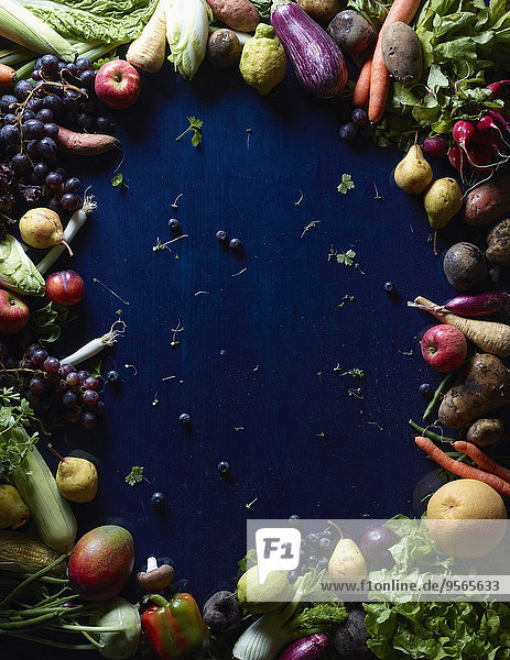 Direkt über dem Schuss frisches Gemüse und Früchte bilden einen Kreis auf blauem Tisch.