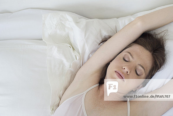 Woman lying in bed stretching arms over head