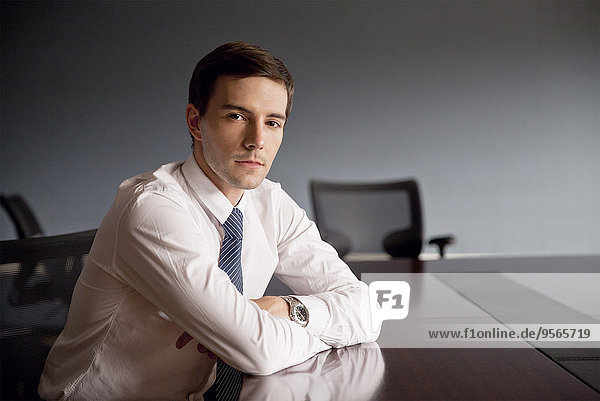 Geschäftsmann am Konferenztisch sitzend  Portrait