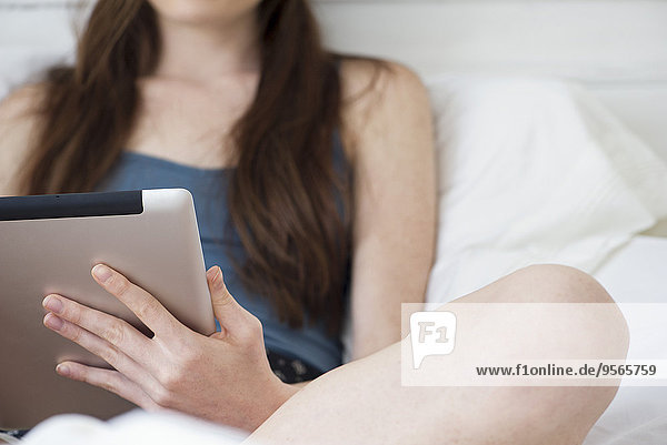 Frau mit digitalem Tablett im Bett