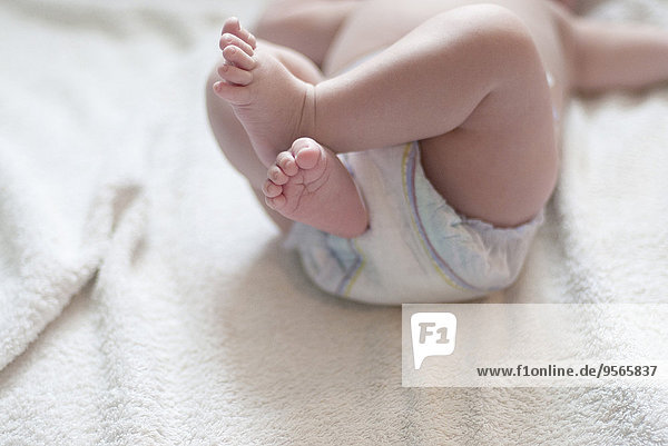 Baby in Windel auf dem Rücken liegend mit hochgezogenen Beinen  abgeschnitten