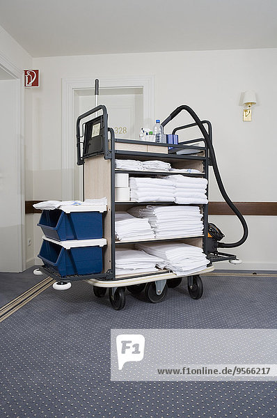 Trolley with room supplies and cleaning equipment in hotel corridor