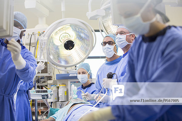 Doctors performing surgery in operating theater  looking at monitor
