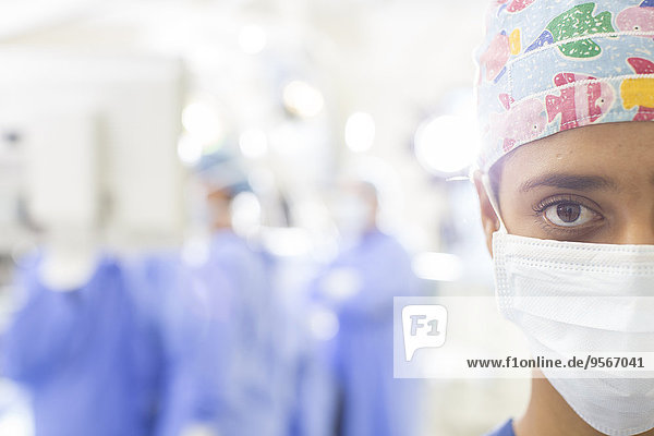 Portrait des maskierten Chirurgen mit unscharfer Krankenhauseinstellung im Hintergrund