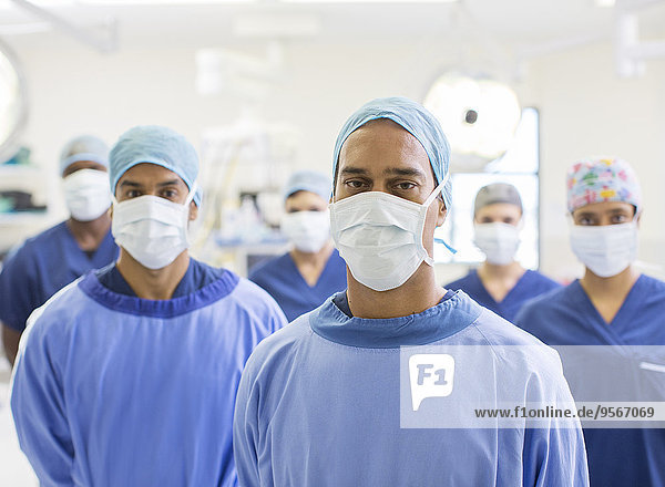 Group portrait of team of masked surgeons in hospital