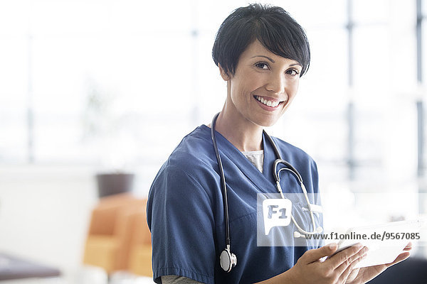 Portrait of female doctor with stethoscope around neck  holding digital tablet