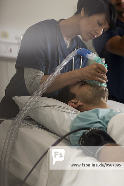 Arzt mit Sauerstoffmaske über dem Mund des Patienten auf der Intensivstation