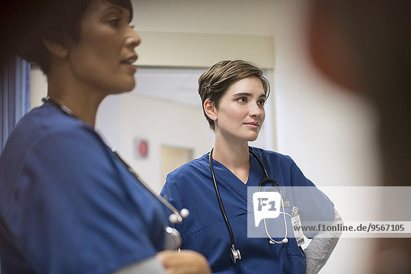 Two female doctors wearing navy blue scrubs  talking in hospital