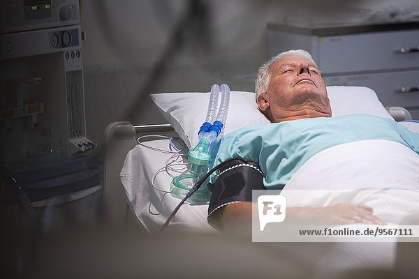 Patient lying in bed next to oxygen mask in intensive care unit