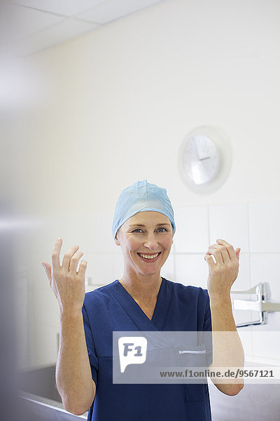 Porträt einer lächelnden Ärztin mit OP-Mütze und OP-Kittel im Krankenhaus