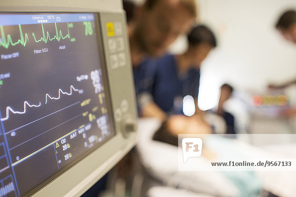 Herzfrequenzmonitor  Patient und Ärzte im Hintergrund auf der Intensivstation
