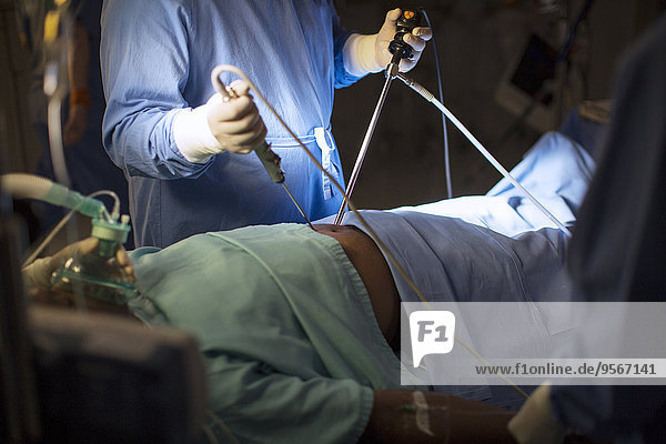 Chirurg mit medizinischem Werkzeug und Durchführung laparoskopischer Operationen im Operationssaal