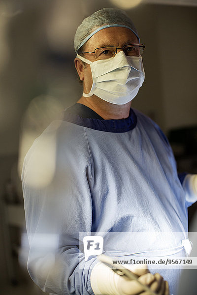 Chirurg mit OP-Maske  Mütze  Handschuhen und Kittel im Operationssaal