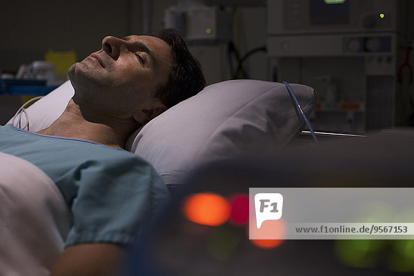 Patient lying in hospital bed in intensive care unit  medical equipment in foreground